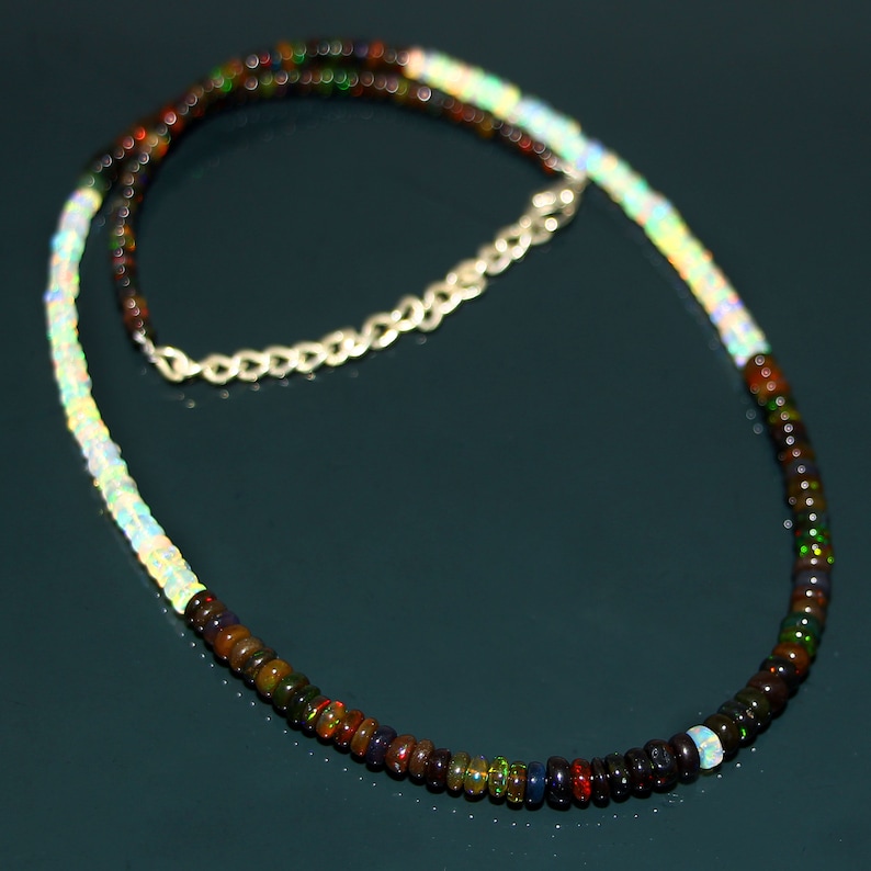 May include: A silver chain necklace with a multi-coloured opal bead strand. The strand is made of alternating white and dark opal beads.
