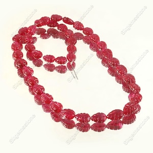 May include: A strand of deep red, translucent gemstone beads carved into a leaf shape. The beads are strung together on a thin wire, creating a continuous loop. Each bead features detailed vein carvings on its surface, reflecting light.