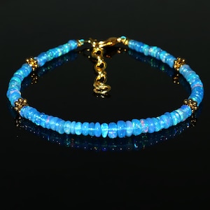 Op de afbeelding: Een delicate blauwe opaal armband met gouden accenten. De armband is gemaakt van kleine, ronde opaal kralen en heeft een gouden sluiting.