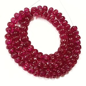 May include: A strand of deep red ruby beads, each bead is faceted and has a pumpkin shape.