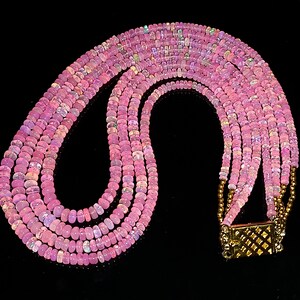May include: A multi-strand necklace made of pink opal beads with a gold clasp.
