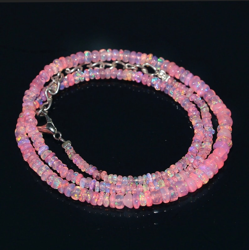 Puede incluir: Un collar de cuentas de &oacute;palo rosa con un cierre plateado. El collar est&aacute; hecho de peque&ntilde;as cuentas redondas que est&aacute;n enhebradas en una cadena plateada.