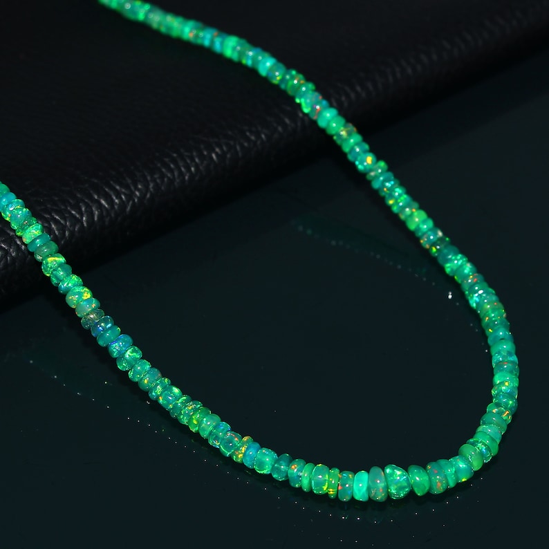 Puede incluir: Un collar de cuentas de &oacute;palo verde con un acabado iridiscente brillante. El collar est&aacute; hecho de peque&ntilde;as cuentas redondas que est&aacute;n enhebradas en una cadena fina.