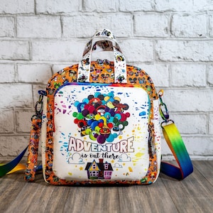 May include: White backpack with a colorful print of Disney characters and balloons. The backpack has a top handle and a long adjustable strap. The text "ADVENTURE is out there" is printed on the front of the bag.