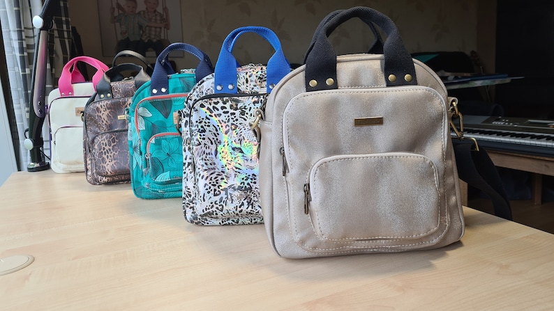 May include: Five different patterned backpacks with adjustable straps. The backpacks are in various colors, including white, brown, green, black, and beige.