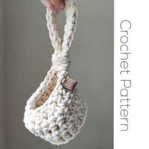 May include: A white crocheted hanging planter with a brown leather tag that says "The Crochet Nook".