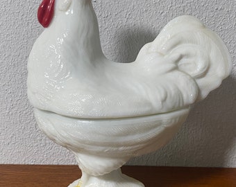 May include: White milk glass rooster shaped candy dish with a red comb and yellow feet. The dish has a lid and is a vintage item.