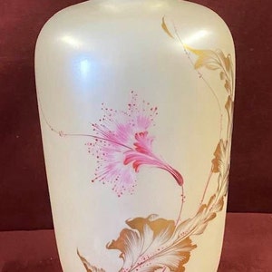 May include: A white ceramic vase with a gold rim and a pink and gold floral design.