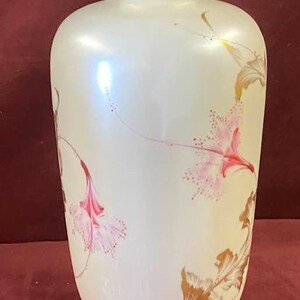 May include: A white ceramic vase with a gold rim and floral designs. The vase has a pearlescent finish and features pink and gold flowers.