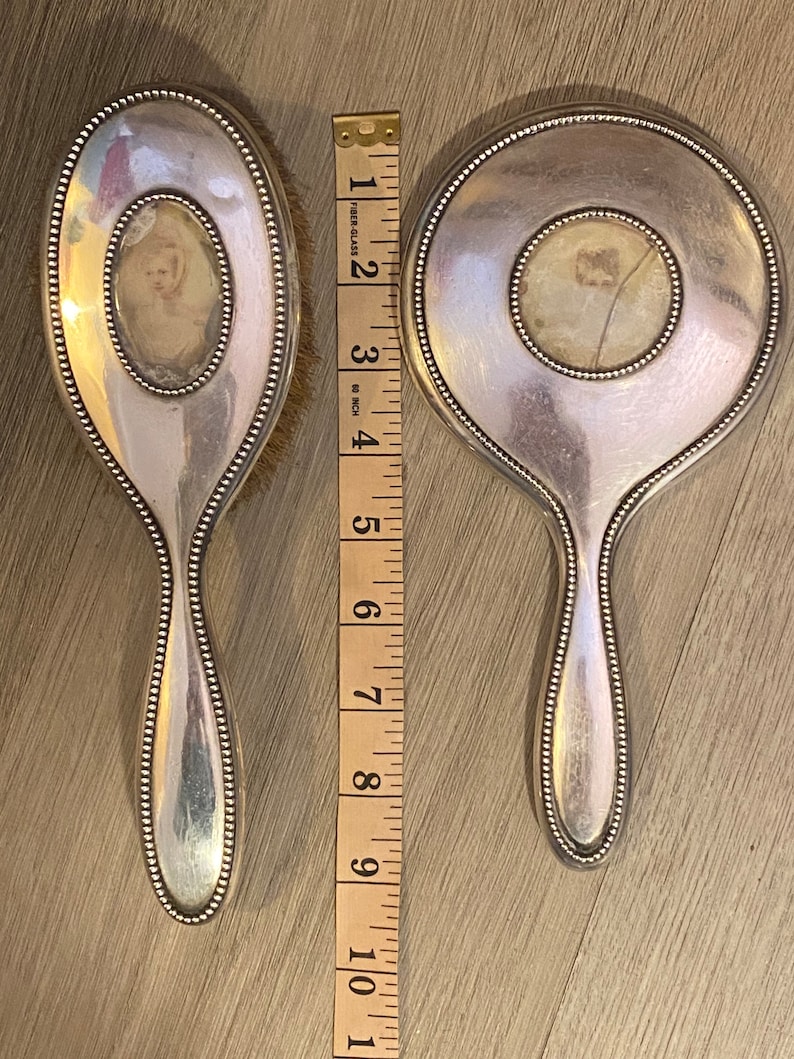 Puede incluir: Dos espejos de mano plateados con bordes perlados. Cada espejo tiene un peque&ntilde;o espejo ovalado en el centro. Los espejos miden 25,4 cm de largo.