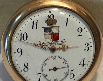 May include: A gold pocket watch with a white face and black Roman numeral hour markers. The watch has a small secondary dial at the bottom and a crest with a crown and the text "Aux Armes De Lyon" in the centre.