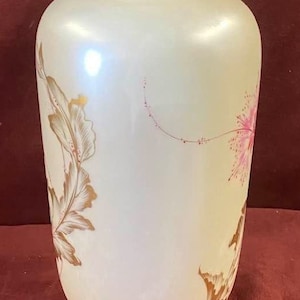 May include: A white ceramic vase with a gold rim and delicate pink and gold floral designs. The vase has a pearlescent finish.
