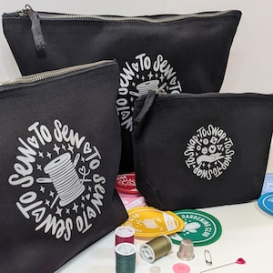 May include: Three black zippered pouches with white text. The largest pouch has the text "To Sew To Sew To Sew" in a circle. The middle pouch has the text "To Sew To Sew To Sew" in a circle. The smallest pouch has the text "To Swap To Swap To Swap" in a circle.