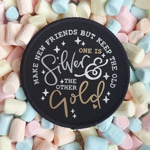 May include: Black round patch with white and gold lettering. The text reads "Make new friends but keep the old. One is silver & the other gold."