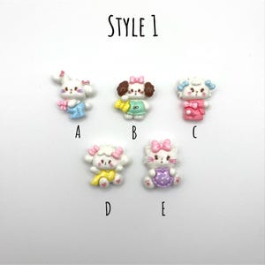 May include: Five different styles of white resin animal charms with pink bows. The charms are labeled A through E. Style 1.