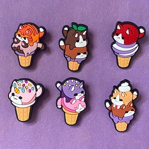 Peut inclure: Six charmes en forme de cornet de glace colorés représentant différents chats de dessin animé avec des pépites et des garnitures. Les charmes sont en silicone et sont parfaits pour ajouter une touche amusante et fantaisiste à vos accessoires.