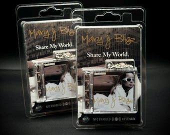 May include: Two clear plastic packages each containing a keychain. The keychains feature a small image of Mary J. Blige and the text "Mary J Blige Share My World." The packages also have "NFC ENABLED KEYCHAIN" printed on them.