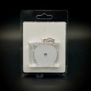 May include: A clear plastic packaging with a white backing card. A small, round, white disc with a silver chain is inside the packaging.