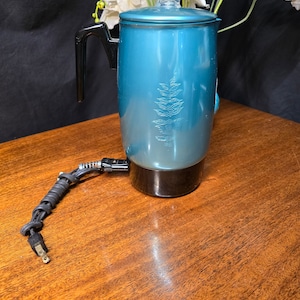 May include: A teal blue electric coffee percolator with a black handle and base. The percolator has a fern design on the side.