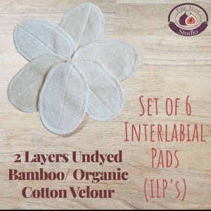May include: A set of six undyed, oval-shaped interlabial pads made from bamboo and organic cotton velour. The pads are arranged in a flower-like pattern on a wooden surface. Text on the image reads "Set of 6 Interlabial Pads (ILP's)" and "2 Layers Undyed Bamboo/Organic Cotton Velour."