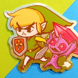 Puede incluir: Una pegatina con una ilustración de dibujos animados de un personaje con pelo rubio, una túnica verde y un escudo, frente a una criatura morada con un gran cristal rosa. El fondo es una división de verde y azul.