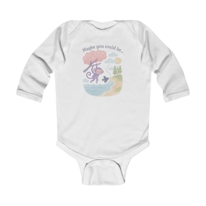 May include: White long-sleeved baby bodysuit with a playful illustration. It depicts a purple monkey swinging from a tree, a butterfly, and the text "Maybe you could be...". The scene is set on a beach with water and trees, creating a charming design.