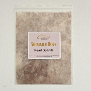 May include: A close-up of a package containing a sheet of shimmer rock paper with a pearl sparkle finish. The package has a label that reads "Glazey Designs" and "Shimmer Rock Pearl Sparkle".