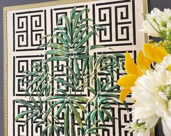 May include: A black and white geometric pattern with a gold frame. The pattern is a Greek key design. Green palm leaves are painted on top of the pattern.