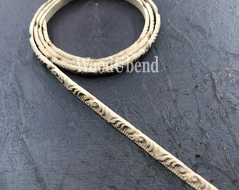 May include: A close-up of a beige, decorative trim with a detailed, ornate design. The trim is flexible and can be used for a variety of craft projects.
