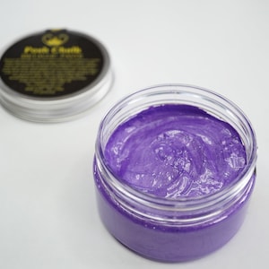 May include: A purple hair color cream in a clear jar with a black lid. The lid has a gold crown and the text "Punk & Chill" on it.