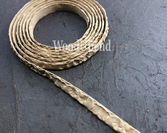 May include: A beige, textured, decorative trim with a repeating pattern. The trim is rolled up in a coil.