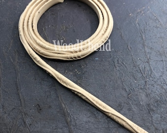 Puede incluir: Un cordón de cuero beige con un patrón decorativo. El cordón está enrollado y tiene una superficie texturizada.