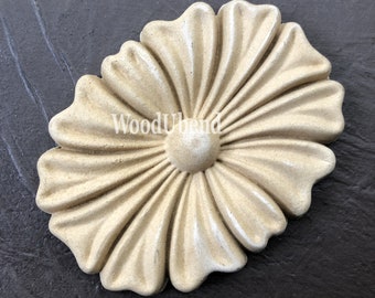 May include: A beige wooden flower-shaped decorative accent with a raised center. The flower has a slightly distressed look and is made of wood.