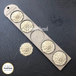 May include: A light beige wooden decorative element with a floral design. The element is part of a set, with three pieces attached to a rectangular holder and one separate. The holder has the text "WoodUbend" printed on it.
