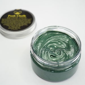 May include: A green face mask in a clear glass jar with a black lid. The lid has a gold crown and the text "Post Chill" in gold lettering.