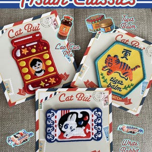 May include: An assortment of iron-on patches featuring Asian-inspired designs. Includes a red jar patch with a figure, a tiger balm patch, and a white rabbit patch. The text "Asian Classics" is at the top.