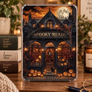 May include: A clear protective tablet case featuring a detailed illustration of a dark, gothic bookstore storefront with the text SPOOKY READS, surrounded by orange pumpkins, spiderwebs, autumn foliage, a black cat, and a full moon in the sky.