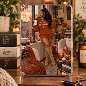 May include: A rectangular mirror with a clear frame reflecting a scene of a person in a rust-coloured jumper dress and tan boots holding a coffee cup. The reflection shows a cosy room with books, candles, and a window view of autumn trees.