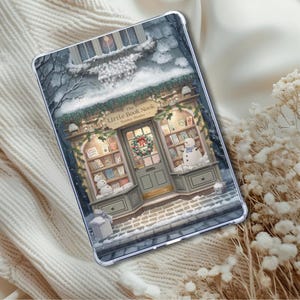 May include: A clear tablet case with a wintery illustration of "The Little Book Nook." The image shows a snowy bookstore with a wreath, snowmen, and bookshelves. The case is displayed on a white, textured surface.