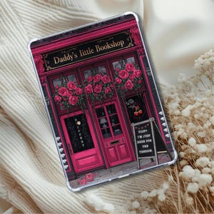 May include: A tablet case featuring a pink illustration of a bookstore facade with the text "Daddy's Little Bookshop." The design includes pink roses, a chalkboard sign, and a door.
