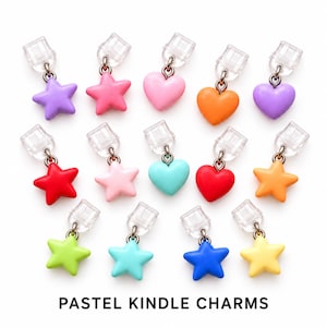May include: A collection of fourteen colourful charms in star and heart shapes, each attached to a clear plastic clip. The charms feature solid colours including red, orange, yellow, green, blue, purple, and pink. Text reads: PASTEL KINDLE CHARMS.