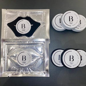 May include: Two silver pouches containing black lip masks with the text "ISHTA BOUIUIK COLLAGEN LIP MASK" and the letter "B" in a circle.  Four black containers with the text "ISHTA BOUIUIK ARNICA LIP BALM" and the letter "B" in a circle.