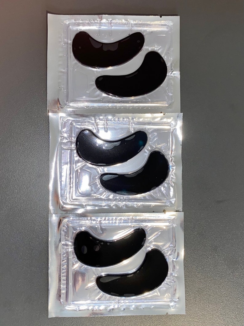 May include: Three individual packages of black under-eye patches. Each package contains two crescent-shaped patches.