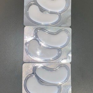 May include: Three individual packages of under-eye patches. Each package contains two crescent-shaped patches in a clear plastic tray.