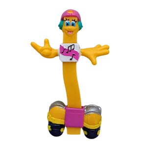 May include: A yellow and pink toy figure with a blue hat and a pink shirt with musical notes. The figure is on roller skates and has a friendly face.