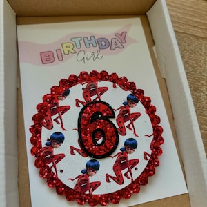 K&ouml;nnte beinhalten: Rote Glitzer-Geburtstagskarte mit einem roten und schwarzen Marienk&auml;fer-Design und der Zahl 6 in der Mitte. Die Karte tr&auml;gt oben den Schriftzug "Birthday Girl".