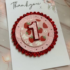 May include: A pink and red glitter card with the number one on it. The card says "Thank you" and has a strawberry pattern.