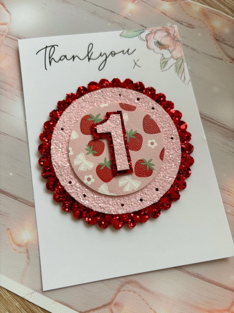 May include: A pink and red glitter card with the number one on it. The card says "Thank you" and has a strawberry pattern.
