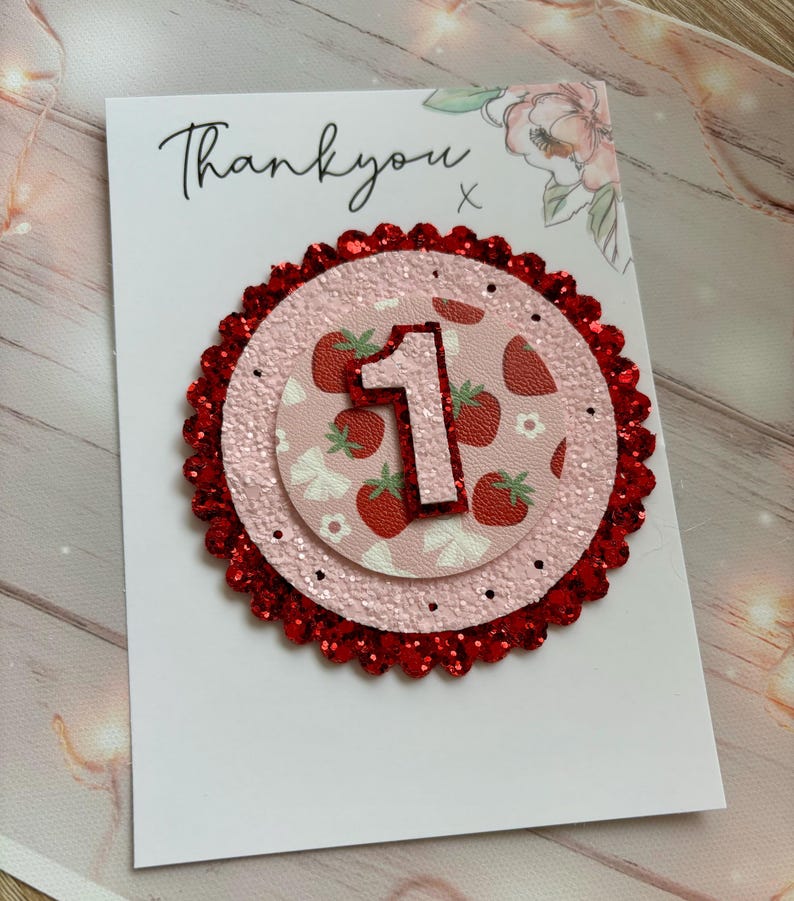 May include: A white card with the text "Thankyou" and a red glitter circle with a pink circle inside. The pink circle has a white number "1" and a strawberry pattern.