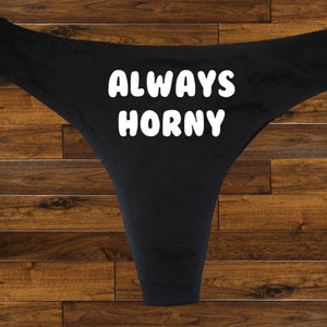 May include: Black lace underwear with the text "ALWAYS HORNY" printed in white.